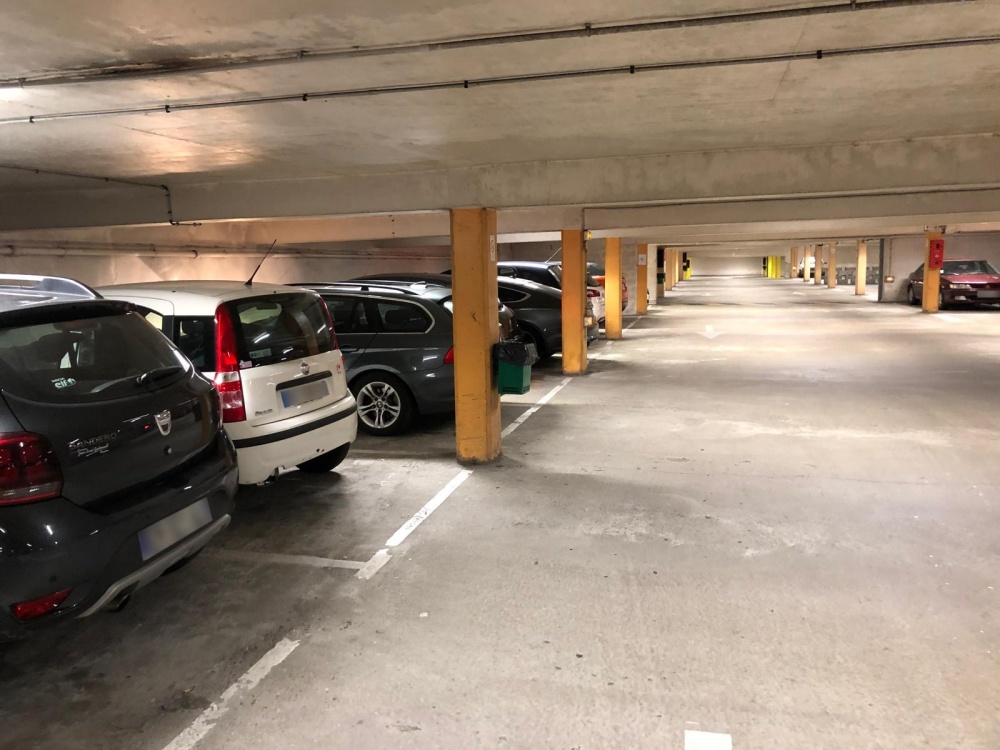 Allée d'un parking souterrain à Vannes, voitures garées entre les piliers jaunes